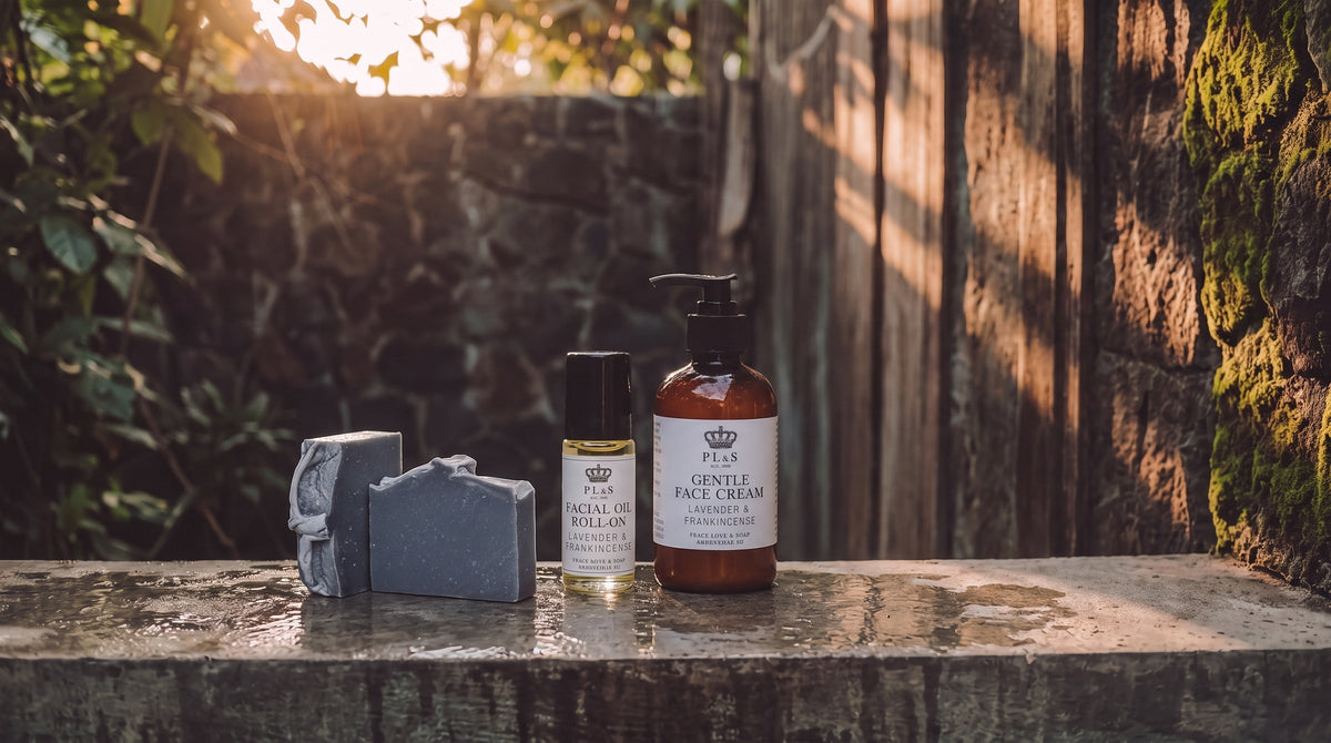 Peace Love & Soap Face collection featuring face cream, face serum, facial oil roll-on, and one unwrapped Charcoal Detox soap bar in a moody garden setting