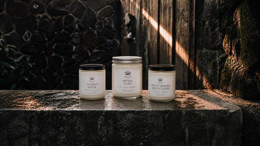 Peace Love & Soap Candles collection featuring Golden Hour, Hotel Luxe, and Great Smoky Mountains soy candles in a moody garden setting