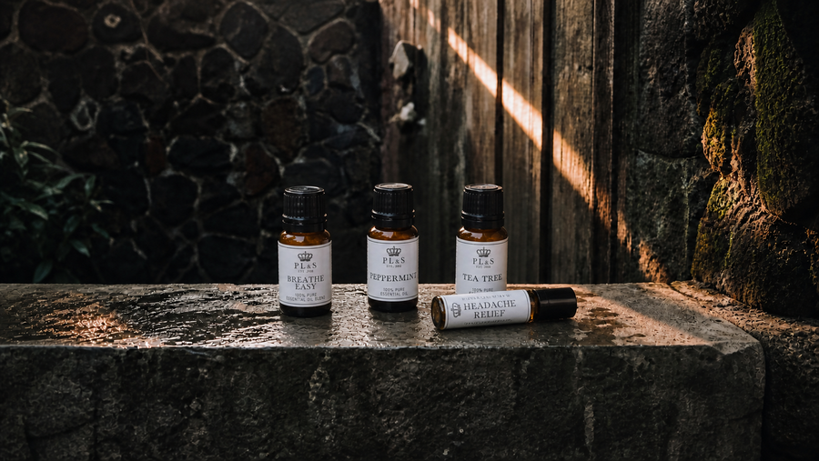 Peace Love & Soap Essential Oils collection featuring Breathe Easy, Peppermint, Tea Tree, and Headache Relief in a moody garden setting