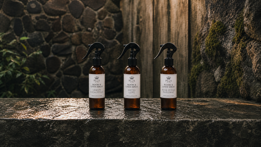 Peace Love & Soap room and linen sprays with clear labels on wet stone in a garden courtyard