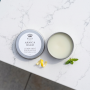 a jar of arnica balm on a marble surface