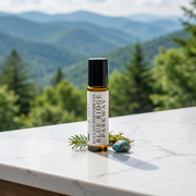 a small bottle of essential oil on a marble surface with a view of mountains and trees