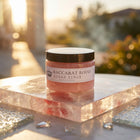 a jar of pink scrub on a marble surface