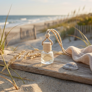 a bottle of perfume on a wood surface with a towel and wheat on the beach