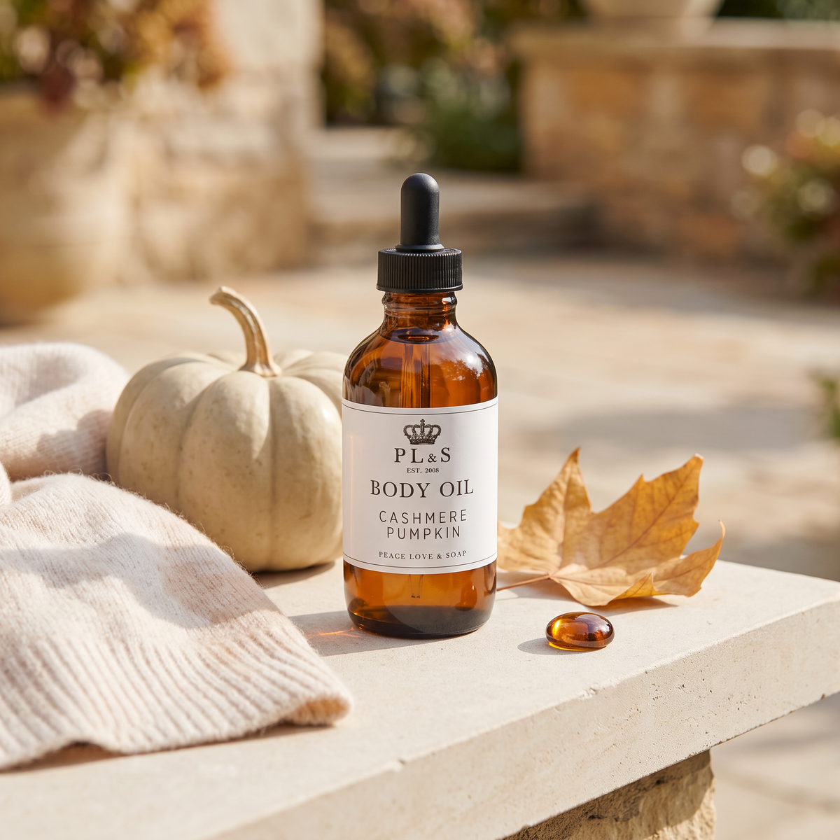 a bottle of body oil next to a pumpkin and a scarf