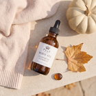 a bottle of oil next to a pumpkin and a blanket