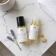 two bottles of essential oil next to a towel and lavender