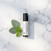 a small bottle of essential oil next to a leaf