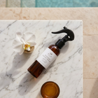 a bottle of spray and a small glass cup on a marble surface