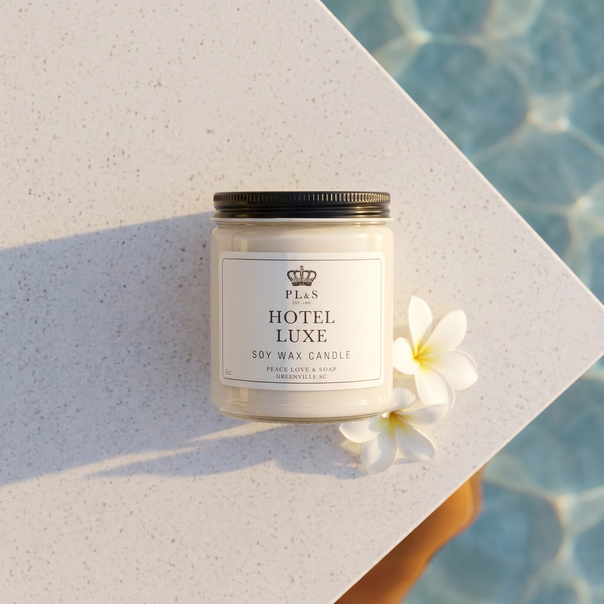 a white candle on a white surface next to a white flower