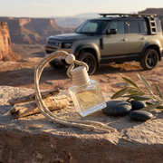 a bottle of perfume and a rope on a rock with a car in the background