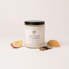 a white candle with a black lid next to a slice of apple