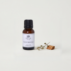 a small bottle of patchouli essential oil next to a small piece of wood